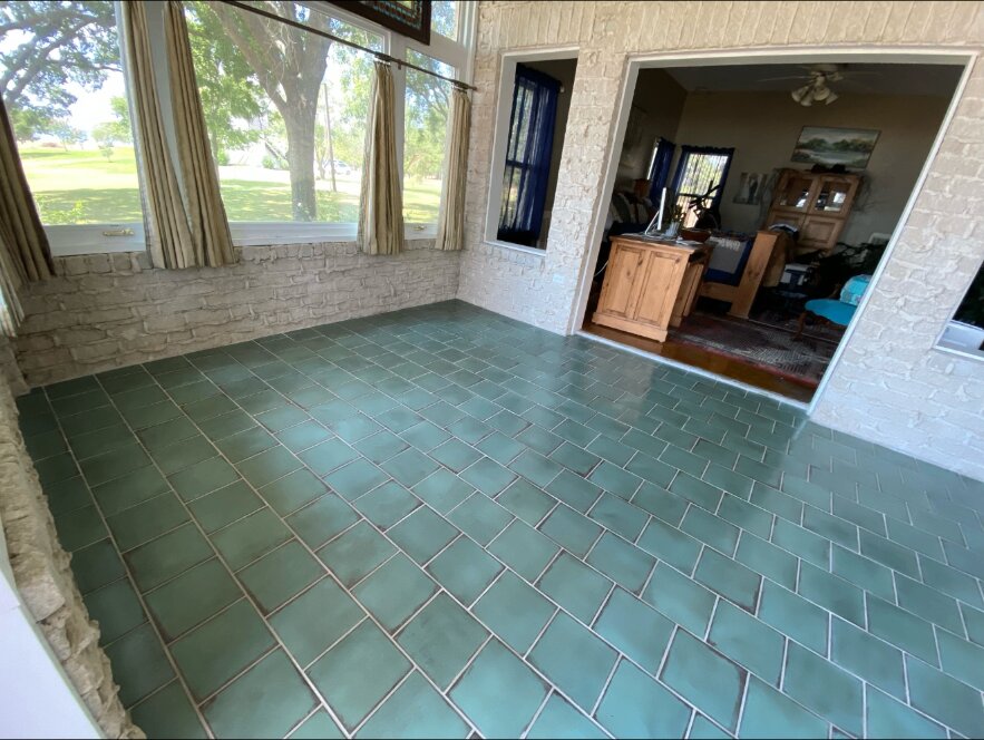 Finished green tile floor beside large windows