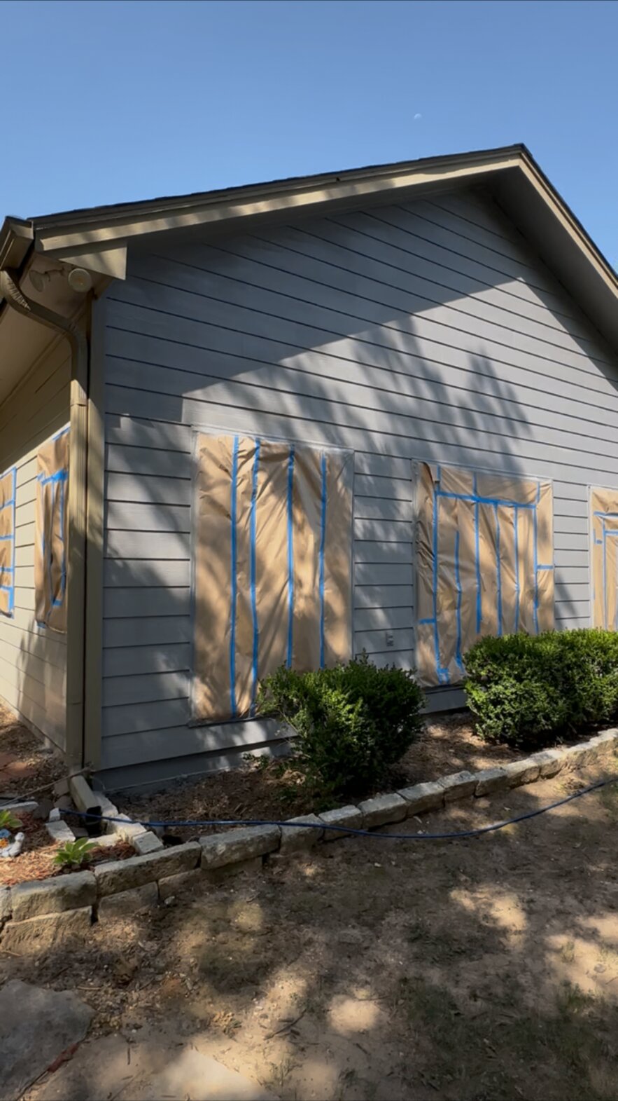 Wider view of a house exterior with masked windows during painting preparation