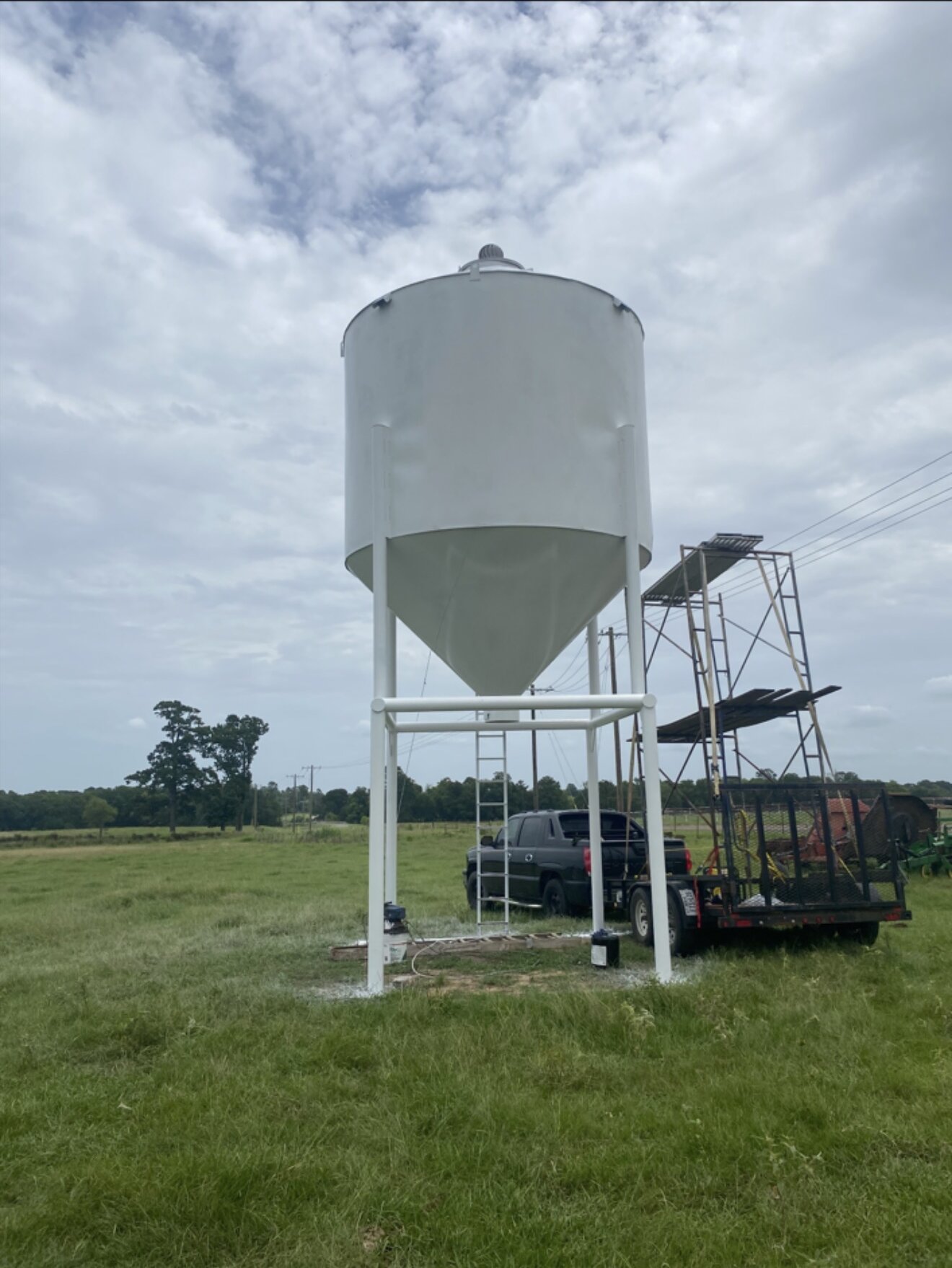 Large white painted tank on a steel stand in a field